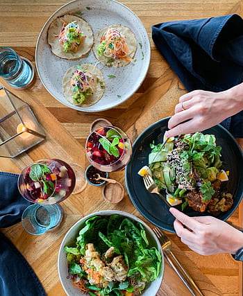 Top view of a vibrant vegetarian meal with tacos, salads, and refreshing beverages on a wooden table. HD phone wallpaper