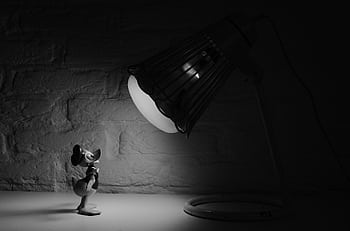 A black and white of a figurine under a spotlight from a lamp against a plain background. HD wallpaper