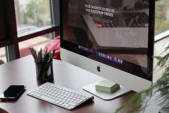 A clean, organized desk setup featuring a computer display, keyboard, and office supplies. HD wallpaper
