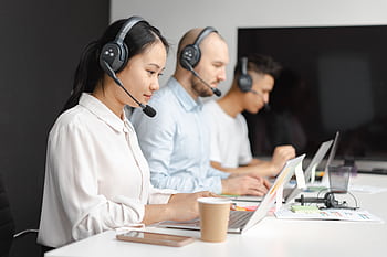 Customer service agents efficiently handle calls using laptops and headsets in a modern office. HD wallpaper