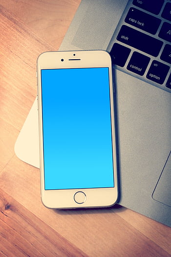 Elegant Apple with a blank screen placed next to a MacBook on a wooden desk. HD phone wallpaper