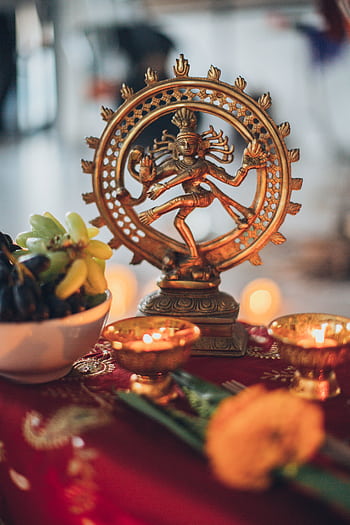 Intricate Shiva Nataraja statue surrounded by traditional offerings and candles on a vibrant altar. HD phone wallpaper