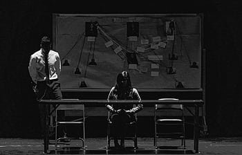 Black and white scene depicting a tense interrogation with suspect and investigator. HD wallpaper