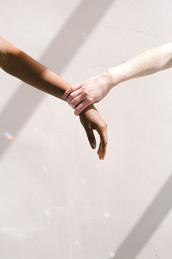 Two people of different ethnic backgrounds holding hands, symbolizing unity and support. HD phone wallpaper