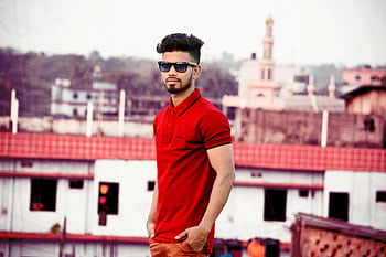 Confident man in red shirt poses outdoors wearing sunglasses on a sunny day. HD wallpaper