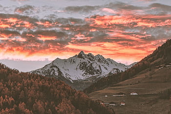 Stunning sunset over snow-capped mountains with vibrant skies and scenic valleys below. HD wallpaper