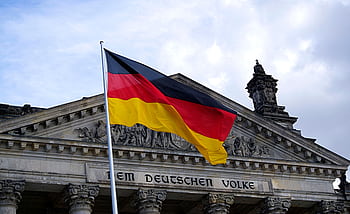 German national flag waving in front of the Reichstag building in Berlin, a symbol of democracy. HD wallpaper