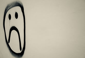 A monochrome of a sad face graffiti on a wall, symbolizing urban emotion. HD wallpaper