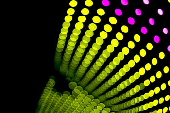Colorful bokeh light patterns with vibrant yellow and pink hues on a black background. HD wallpaper