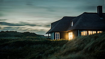A scenic view of a cozy bungalow illuminated at dusk, nestled in lush greenery. HD wallpaper
