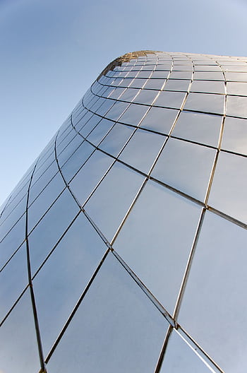 A modern skyscraper with reflective glass panels against a clear sky, showcasing contemporary architecture. HD phone wallpaper