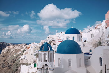 Breathtaking view of Oia's iconic blue-domed churches against a vibrant sky in Santorini, Greece. HD wallpaper