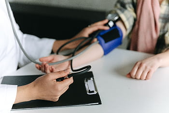 Close-up of a medical professional measuring a patient's blood pressure at a clinic. HD wallpaper