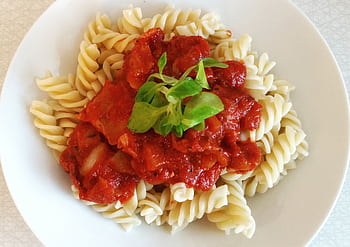 Spirelli pasta topped with rich tomato sauce and fresh greens for a perfect meal. HD wallpaper