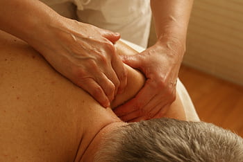 Close-up of a therapist giving a relaxing shoulder massage, enhancing wellness and stress relief. HD wallpaper