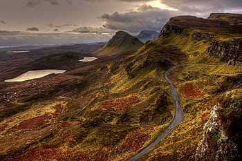 Breathtaking view of the Scottish Highlands with winding roads and serene lakes under a dramatic sky. HD wallpaper