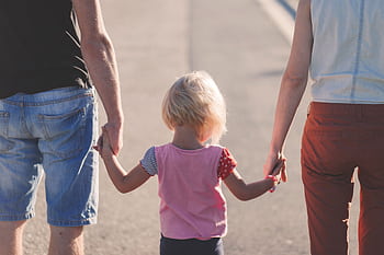 A family enjoying a sunny walk outdoors, hand-in-hand, symbolizing togetherness and love. HD wallpaper