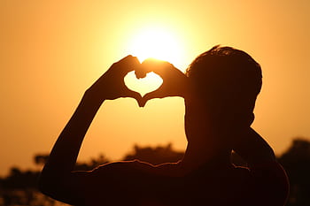A silhouette of hands forming a heart shape against a vibrant sunset in Bangladesh. HD wallpaper