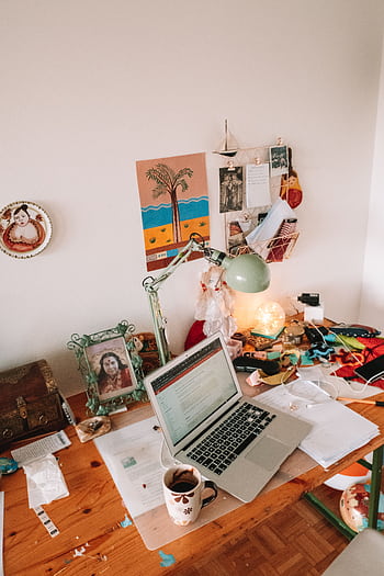 A well-used desk setup with a laptop, lamp, and personal touches, ideal for remote work inspiration. HD phone wallpaper