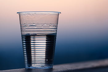 Close-up of a plastic cup filled with water against a soft dusk background. HD wallpaper