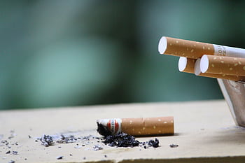 Cigarette with ashes on surface, highlighting tobacco use and health risks. HD wallpaper