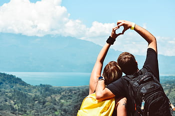 Couple making a heart shape with arms over a beautiful view in Honduras. HD wallpaper