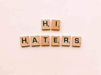 Wooden scrabble tiles spelling 'Hi Haters' on a light beige background. HD wallpaper