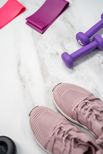 Flat lay of pastel pink fitness gear including sneakers and dumbbells on marble texture. HD phone wallpaper