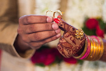 Close-up of hands with henna and jewelry during a traditional Indian wedding ceremony, exchanging rings. HD wallpaper