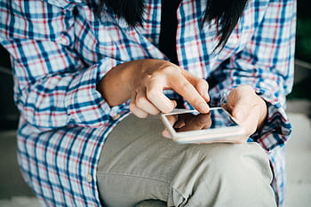 Woman's hands using a smart, wearing plaid shirt, indoors. Close-up shot highlighting touch interaction. HD wallpaper