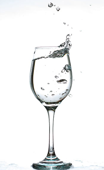 A captivating of water splashing inside a wine glass against a white background. HD phone wallpaper