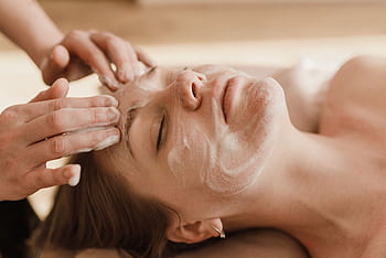 A close-up of a woman receiving a soothing facial massage with a skincare mask. HD wallpaper
