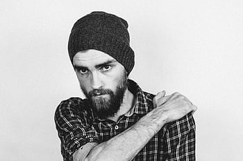 Black and white portrait of a bearded man wearing a beanie and plaid shirt, looking directly at the camera. HD wallpaper