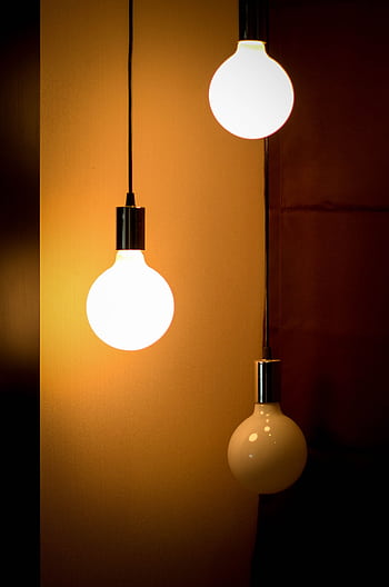 Composition of three glowing light bulbs creating a warm ambiance. Ideal for energy and design themes. HD phone wallpaper