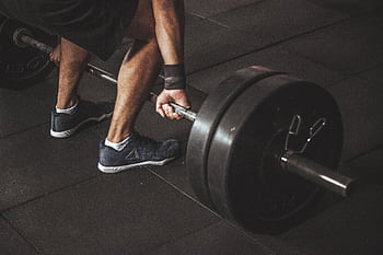 A man lifting a heavy barbell during a gym workout, showcasing strength and fitness. HD wallpaper