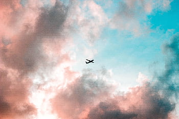 A plane flying through a colorful sky with pink and blue clouds, capturing the essence of travel. HD wallpaper