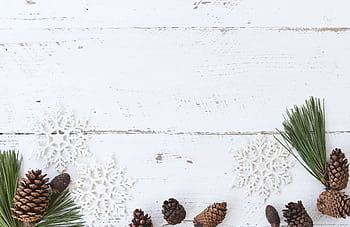Simple holiday arrangement with snowflakes and pine cones on a white wooden background. HD wallpaper