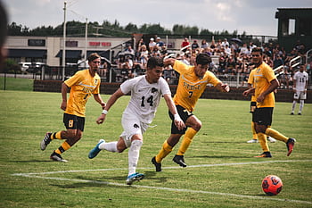 Exciting soccer match with players in motion and enthusiastic spectators. HD wallpaper