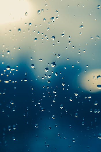 Close-up of raindrops on a window, creating a moody, blurred view outside. HD phone wallpaper