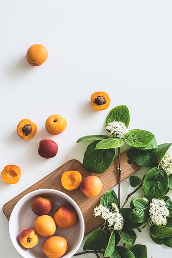 A flat lay of fresh apricots and blossoms on a board showcasing summer freshness. HD phone wallpaper