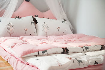 A cozy bedroom with pink bedding and animal patterns, perfect for relaxation. HD wallpaper