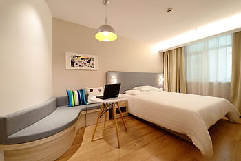 Modern hotel room featuring a bed, laptop, and stylish decor with ample lighting. HD wallpaper