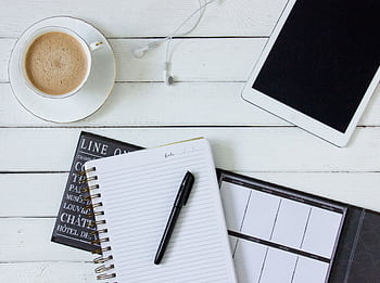 Flat lay of a workspace with notebook, tablet, coffee, and ears on a white desk. HD wallpaper