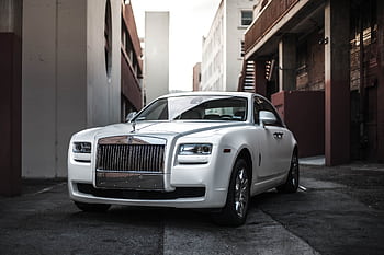 Elegant white luxury car parked in an urban alley, exuding sophistication and style. HD wallpaper