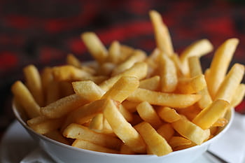 Delicious crispy golden french fries served in a white bowl, perfect for a tasty snack. HD wallpaper