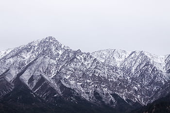 Stunning view of a majestic snow-covered mountain peak under a cloudy sky. HD wallpaper