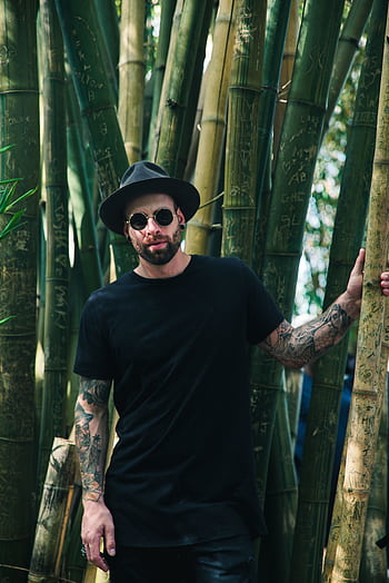 Cool fashion portrait of a man in sunglasses and hat among bamboo trees. HD phone wallpaper