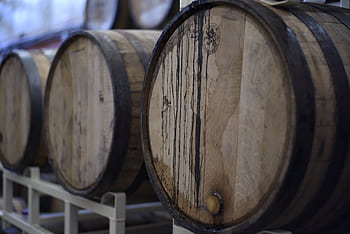 Close-up of wooden wine barrels used for fermentation and storage in a winery cellar. HD wallpaper
