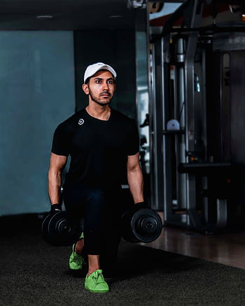 Adult man exercising with dumbbells, focusing on strength training in a gym setting. HD phone wallpaper