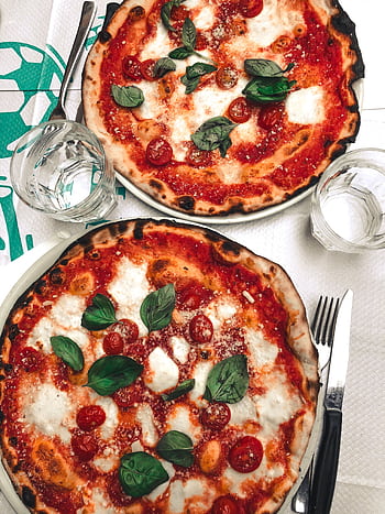Two delicious pizzas topped with mozzarella and basil, perfect for a tasty meal. HD phone wallpaper